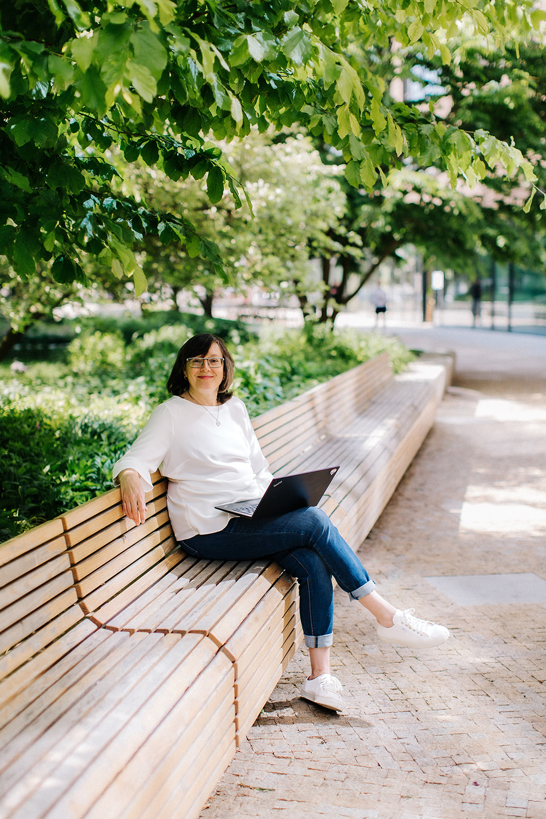 Jana Bodáková při práci na notebooku na lavičce v parku